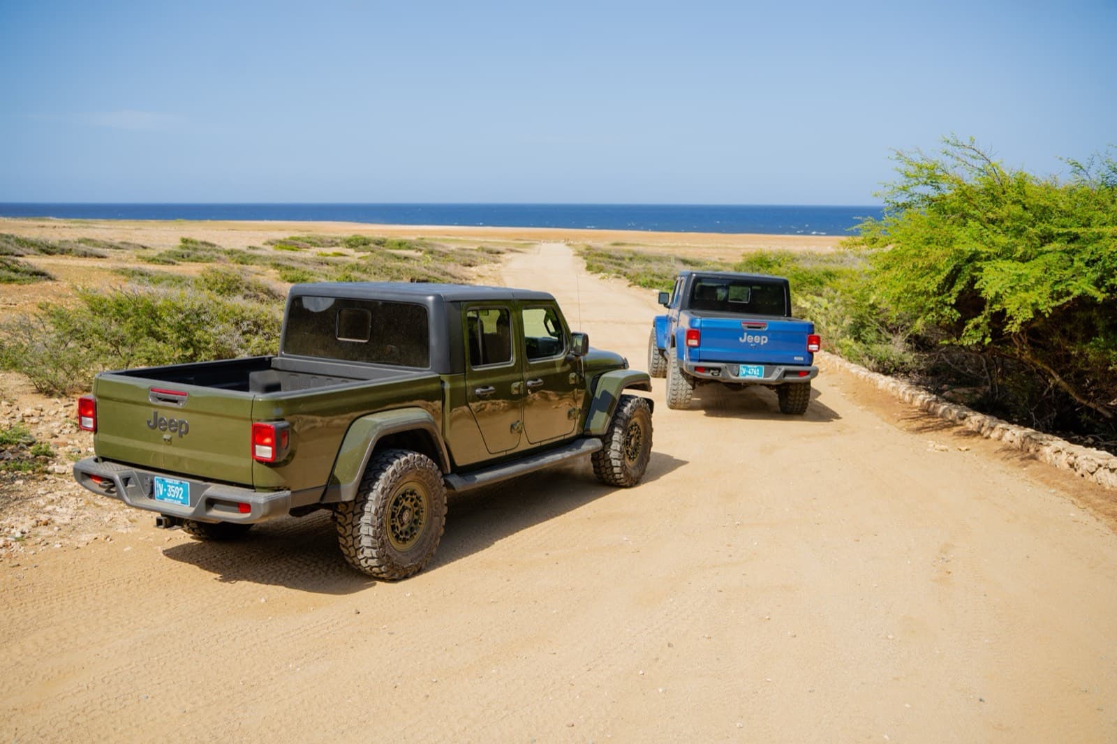 Two Jeep Gladiators on a coastal dirt road